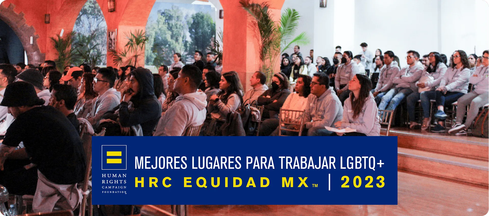 Audiencia sentada en interiores escuchando atentamente con una pancarta sobre los mejores lugares de trabajo LGBTQ+ en México 2023.